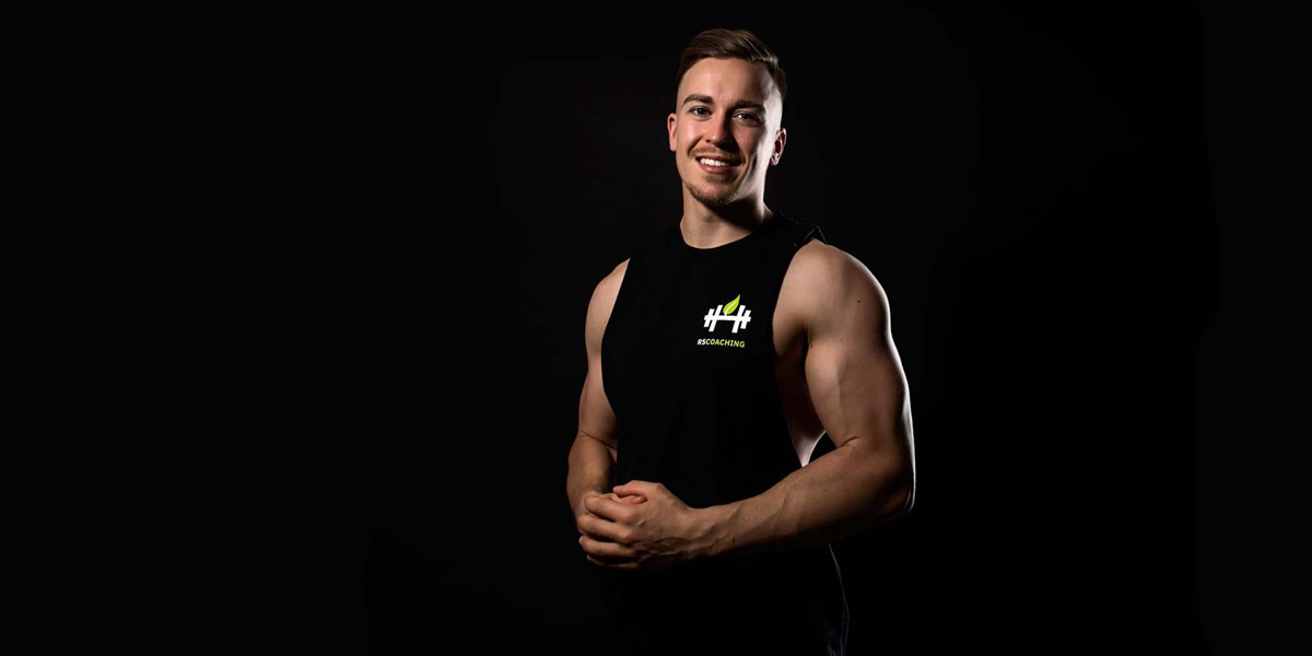 rene-sportler-fitness-trainer-schwarz-top-hintergrund-muskeln-lächeln